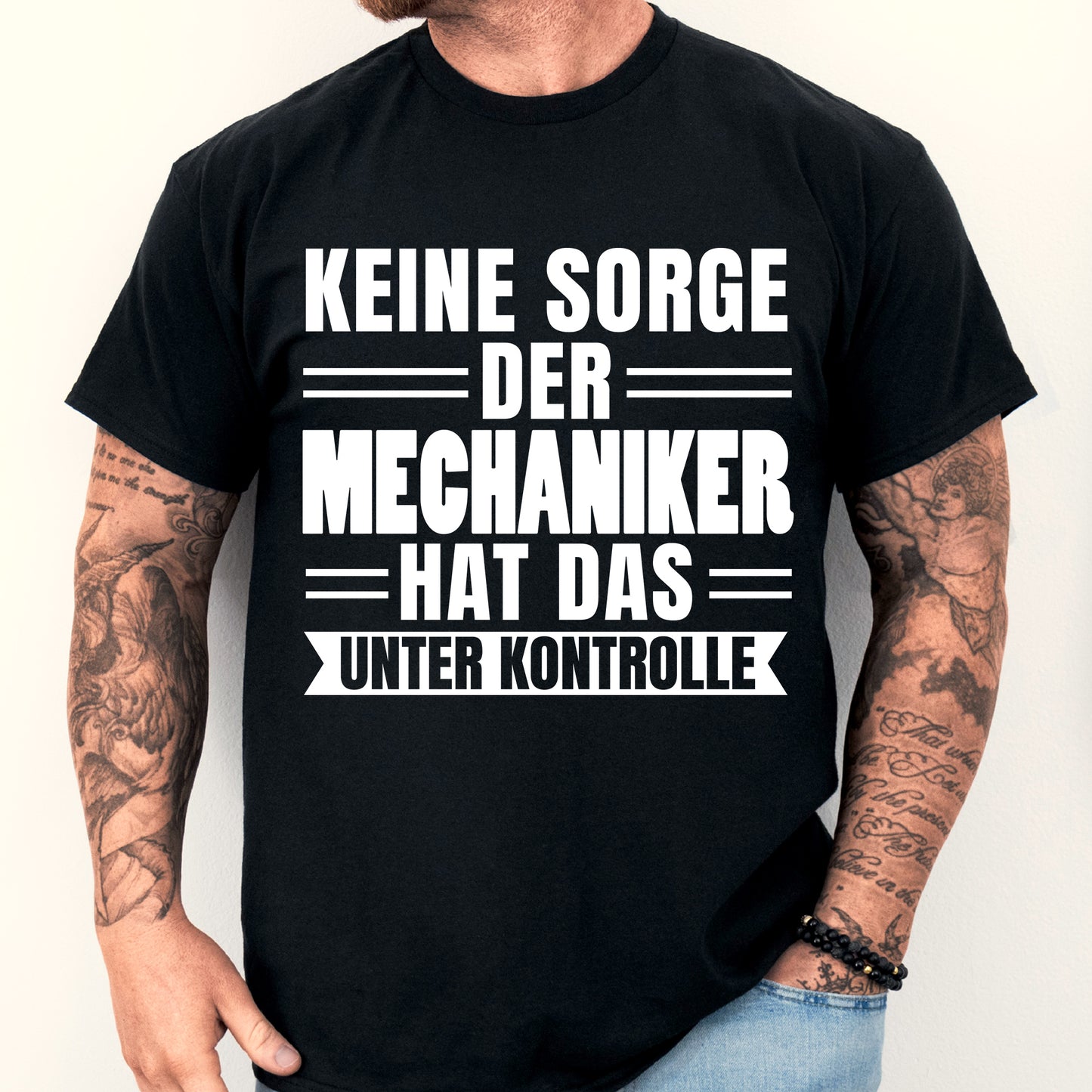 Mechaniker-Shirt mit Aufschrift "Mechaniker hat das unter Kontrolle", getragen von einem Mann.