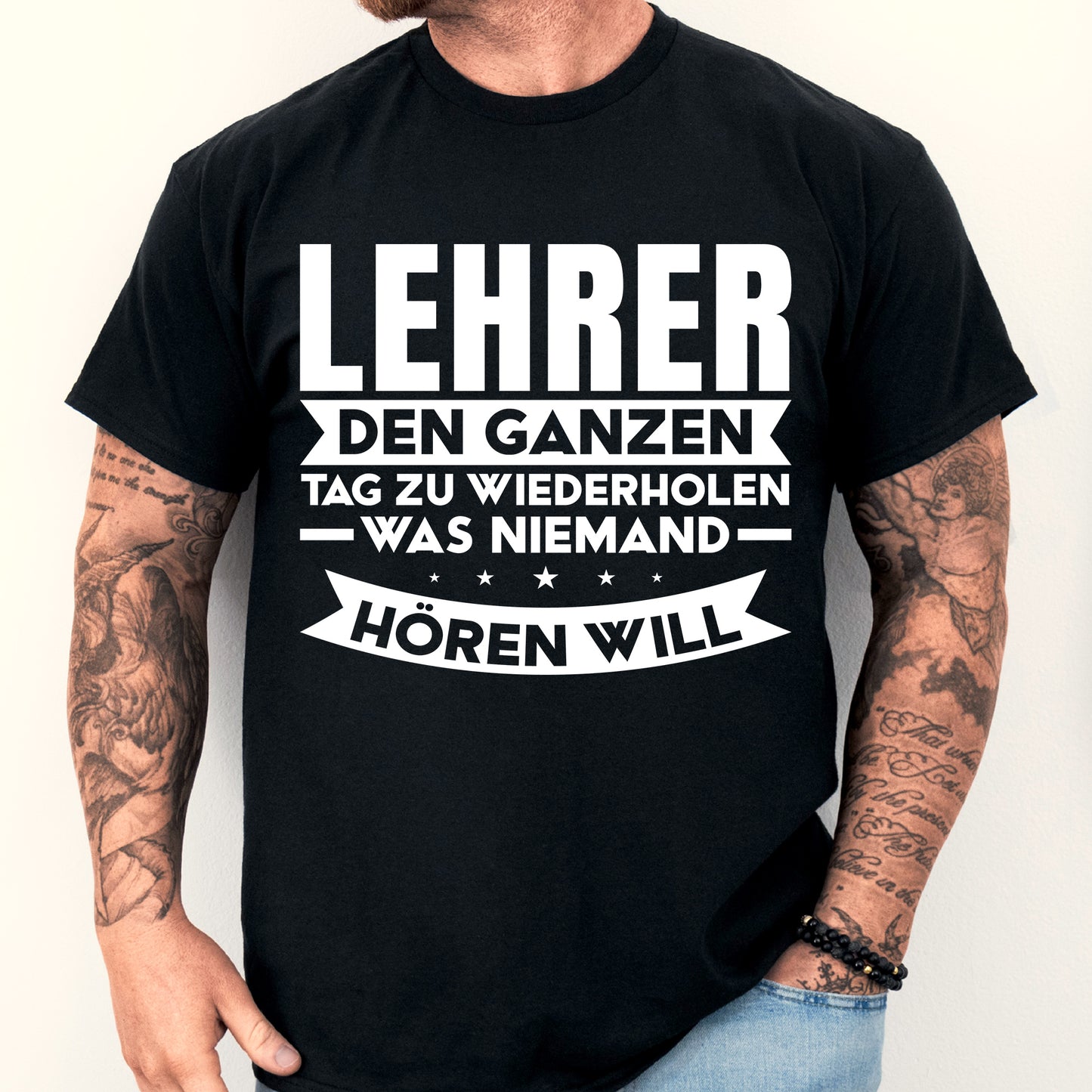 Mann trägt ein humorvolles Lehrer-Shirt mit Aufschrift über das ständige Wiederholen in der Schule.