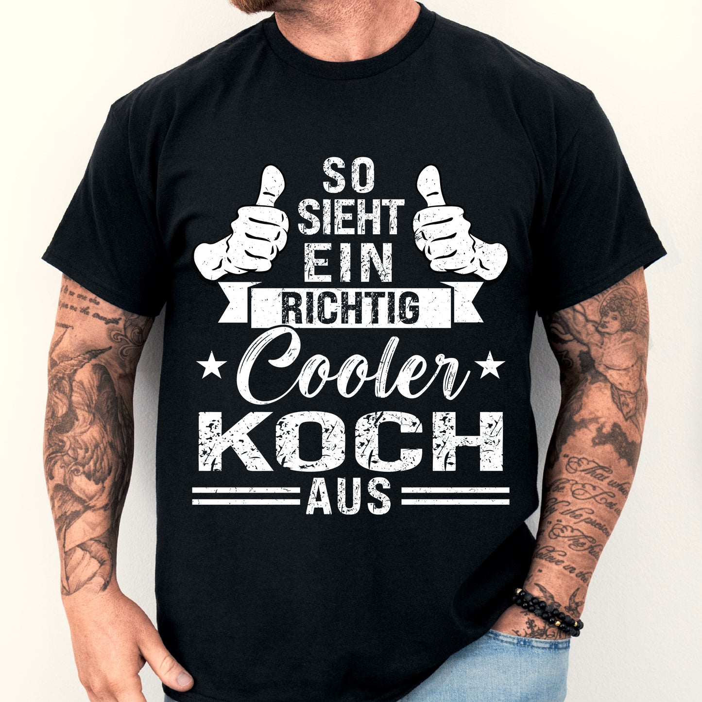 Mann trägt ein T-Shirt mit der Aufschrift "Koch Shirt | richtig cooler Geschenk Kochen Küchenchef" und lächelt in die Kamera.