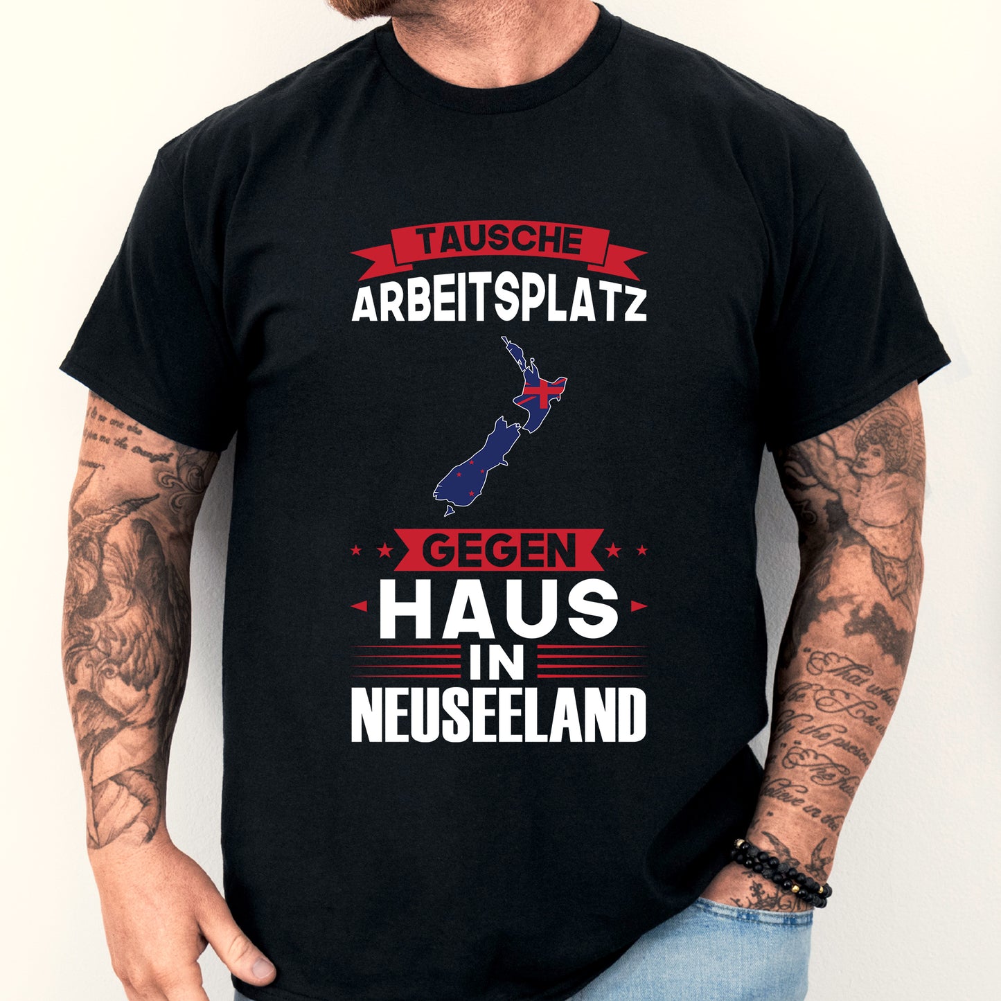 Mann trägt ein T-Shirt mit der Aufschrift "tausche Arbeitsplatz Neuseeländisch" und einer neuseeländischen Flagge.