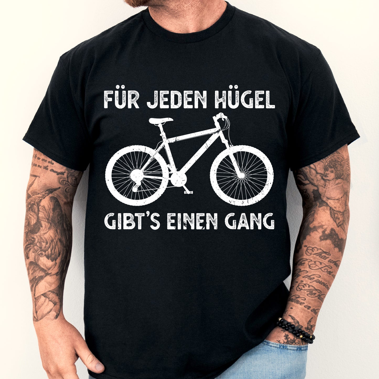 Mann trägt ein T-Shirt mit Fahrrad-Design und dem Text "Für jeden Hügel gibt es einen Gang".