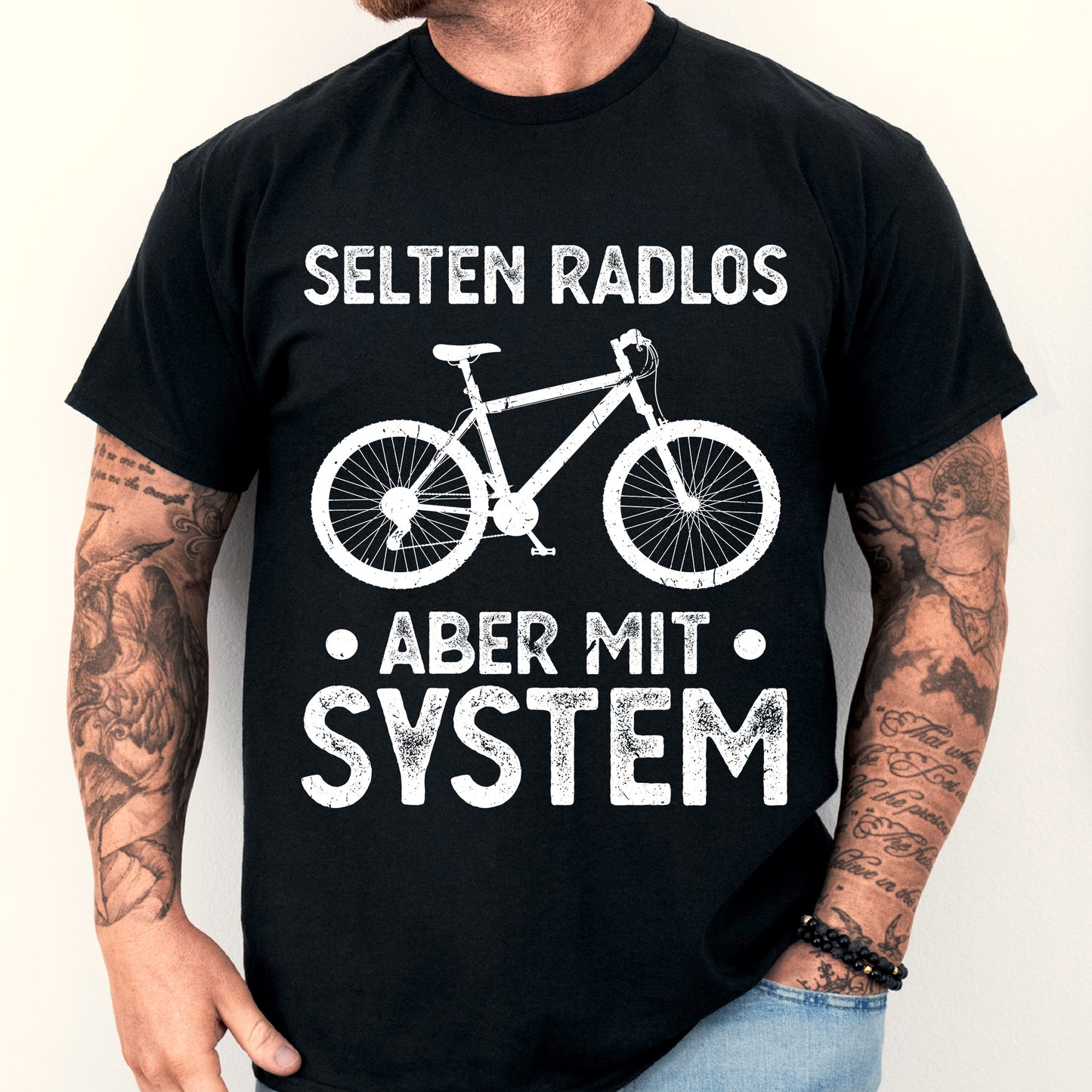 Mann trägt ein T-Shirt mit Fahrrad-Design und dem Text "selten Radlos aber mit System".