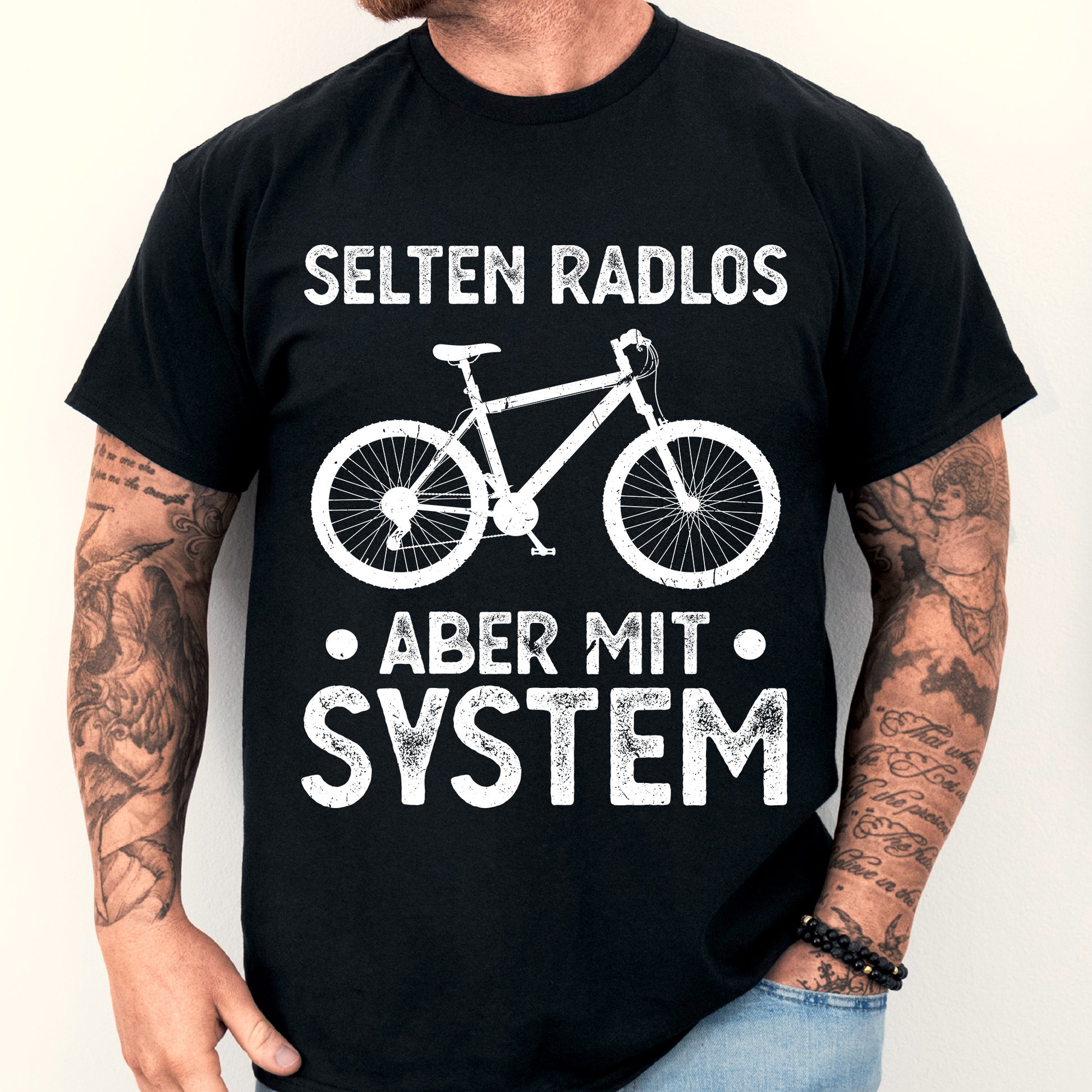 Mann trägt ein T-Shirt mit Fahrrad-Design und dem Text "selten Radlos aber mit System".