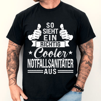 Mann trägt ein schwarzes T-Shirt mit der Aufschrift "Notfallsanitäter" und einem coolen Design, ideal als Geschenk für Sanitäter.